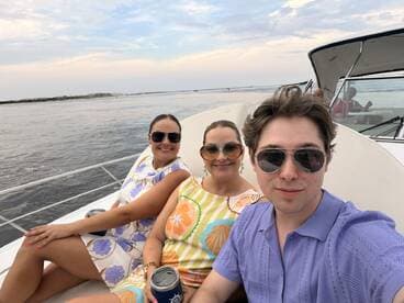 A cheerful group of friends enjoys a boat ride, capturing memories with smiles and drinks in hand — perfect for a day out on the water.