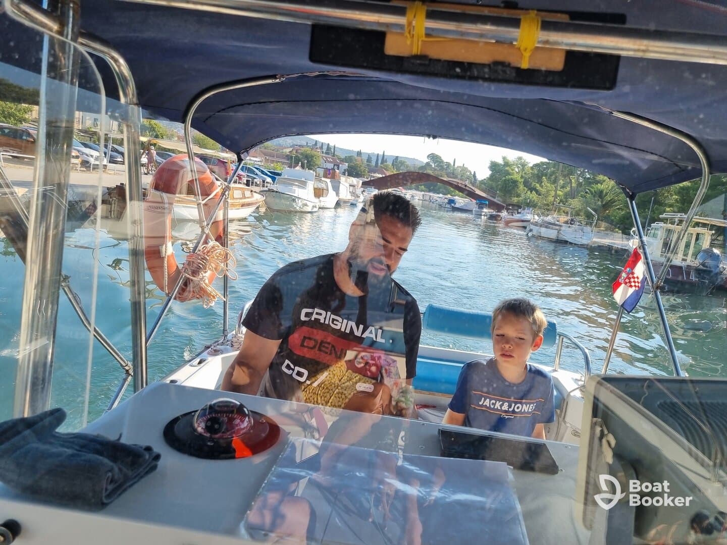 A father and son enjoy time together at the helm of a boat, showcasing a cozy cabin atmosphere perfect for family outings on the water.