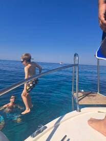 Two children enjoy a fun moment jumping into the clear blue waters from the boat, showcasing the excitement of water activities during a sunny day on the sea.
