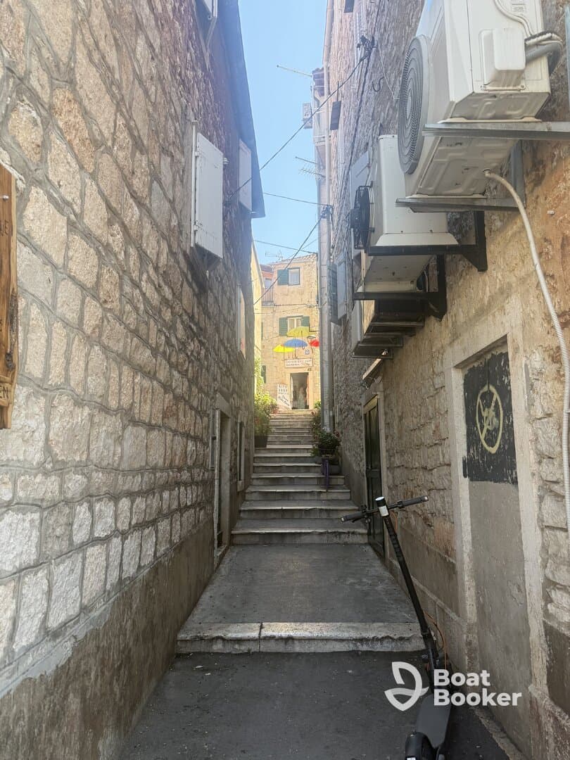 A narrow alleyway with stone walls and steps leading up, showcasing a quaint urban scene. Ideal for exploring local architecture and hidden gems.