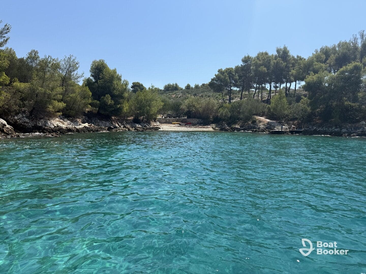 A serene view of a secluded beach surrounded by lush greenery and clear turquoise waters, perfect for a relaxing getaway or exploration.