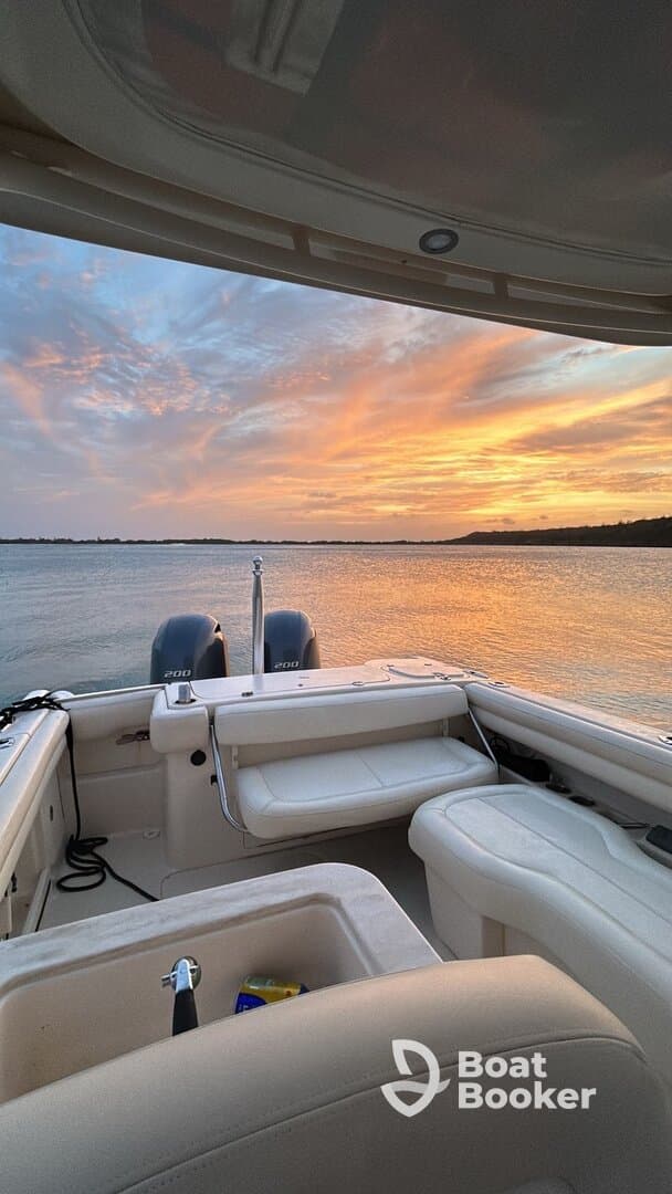 A serene view from inside a boat, showcasing comfortable seating and a stunning sunset over the water — perfect for relaxing cruises.