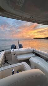 A serene view from inside a boat, showcasing comfortable seating and a stunning sunset over the water — perfect for relaxing cruises.