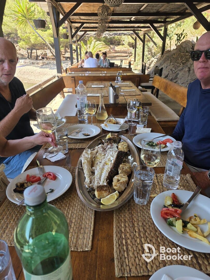 A delicious seafood feast is served at a dining area, featuring grilled fish and fresh salads, perfect for enjoying after a day on the water.
