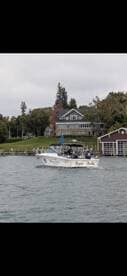 A boat named 'Double Trouble' navigates the water near a picturesque lakeside home, showcasing a perfect day for boating and relaxation.