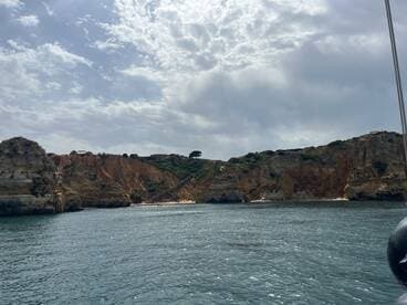 A stunning view of rugged cliffs and a sandy beach, showcasing the natural beauty of the coastline — perfect for scenic boat tours.
