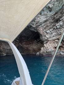 A scenic view from a boat approaching a stunning cave, showcasing the vibrant blue water and rocky formations — perfect for adventure seekers exploring coastal wonders.