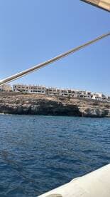 A scenic view of a rocky coastline with buildings perched above the water, captured from a boat — perfect for showcasing beautiful destinations while cruising.
