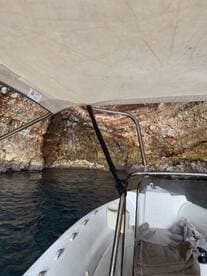 A view from inside a boat's helm area, showcasing the shaded seating and the rocky coastline in the background, perfect for exploring coastal waters.