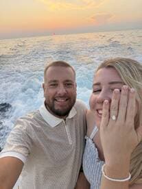 A couple celebrates their engagement against a stunning sunset backdrop while cruising on the water — a perfect moment for romantic adventures.