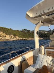 A cozy interior view of a boat showcasing comfortable seating and a scenic backdrop of the coastline, perfect for relaxing while cruising.