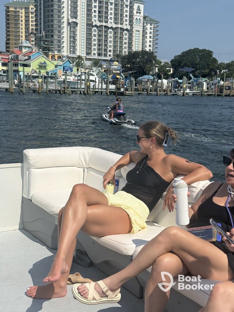 Two friends relax on a boat while enjoying the sun, with a jet ski in the background — a perfect day for boating and fun on the water.