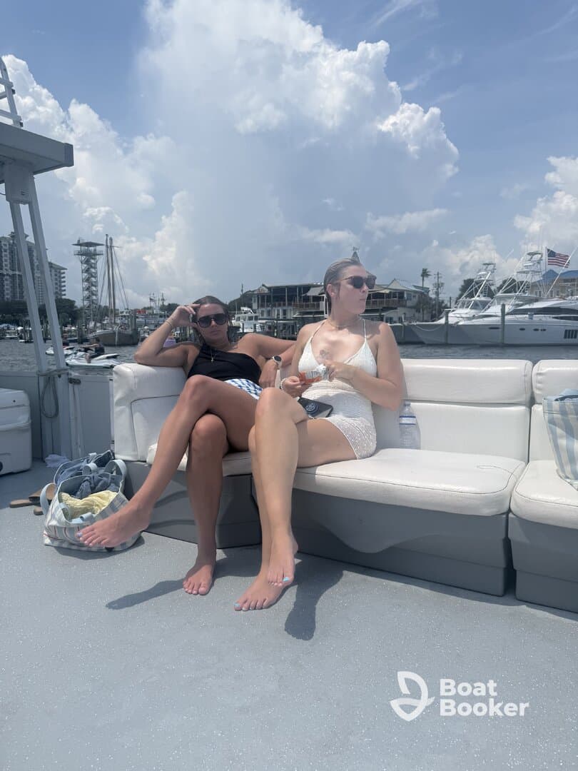 Two friends relax on the deck of a boat, enjoying a sunny day on the water — perfect for a day out with friends.