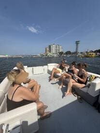 A lively group enjoys drinks aboard a pontoon boat, soaking up the sun and good vibes on the water — perfect for a fun day out with friends.