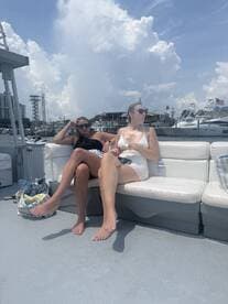 Two friends relax on the deck of a boat, enjoying a sunny day on the water — perfect for a day out with friends.
