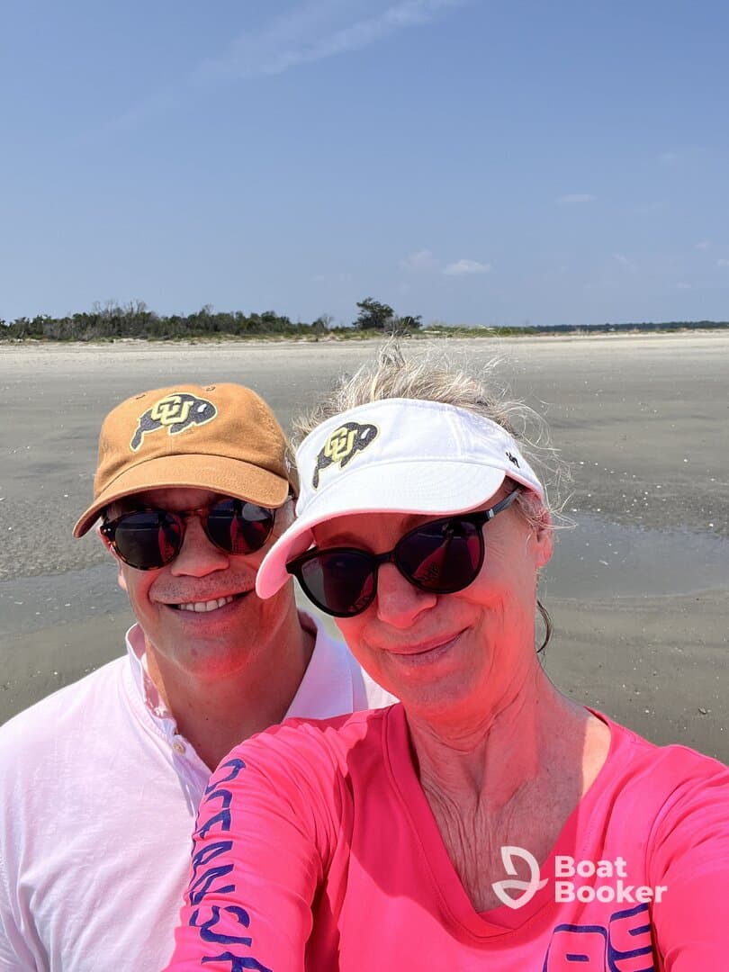 A cheerful couple poses for a selfie on a sunny beach, capturing a memorable moment during their coastal adventure.