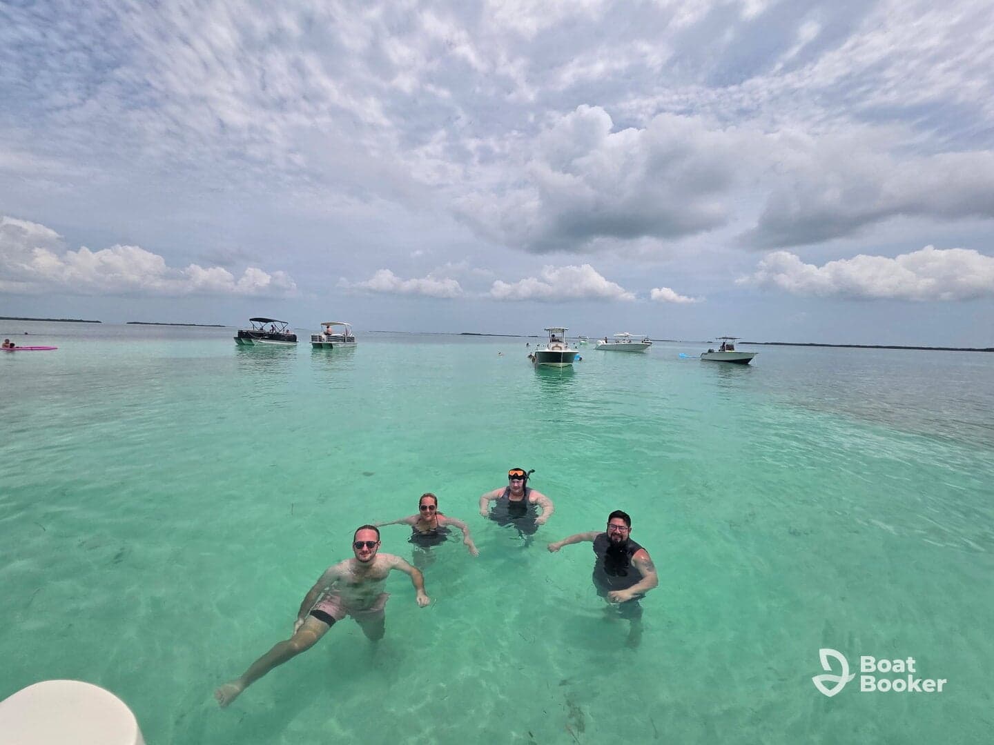 A group of friends enjoys a refreshing swim in crystal-clear turquoise waters, surrounded by boats — a perfect day for snorkeling and relaxation.