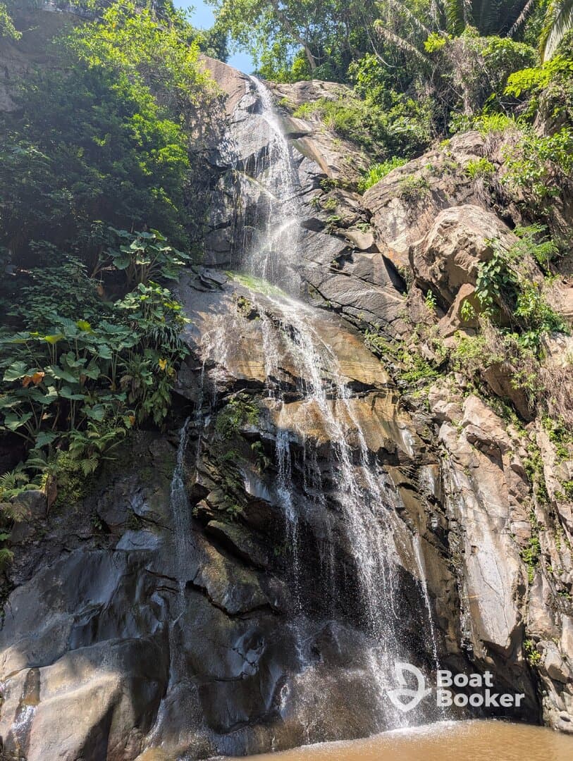 A scenic view of a waterfall cascading down rocky terrain, surrounded by lush greenery, perfect for nature lovers and adventure seekers.