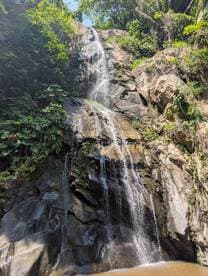 A scenic view of a waterfall cascading down rocky terrain, surrounded by lush greenery, perfect for nature lovers and adventure seekers.
