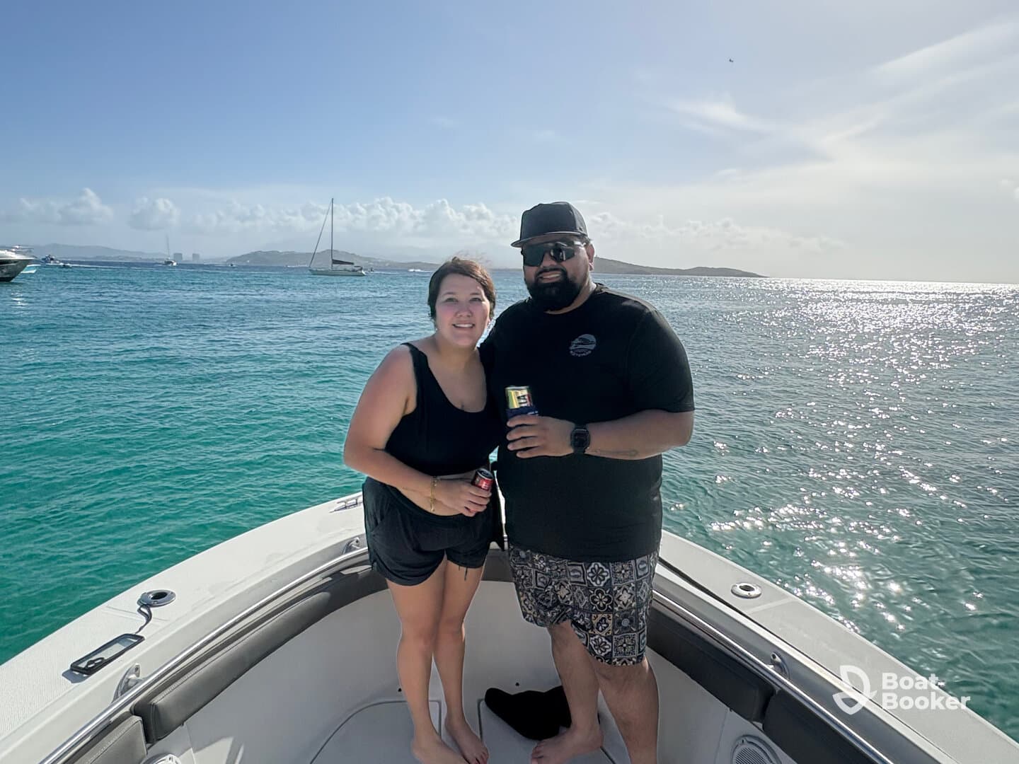 A couple enjoys drinks on the bow of their boat, surrounded by sparkling ocean waters — a perfect moment for celebration and relaxation on the water.