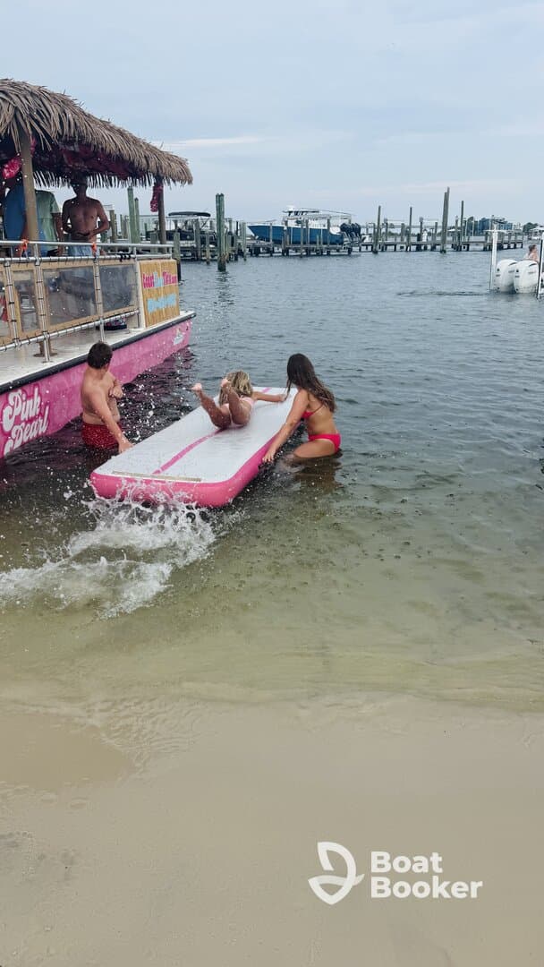 A lively scene of friends enjoying water activities at the beach, with laughter and splashes as they play on a floating mat — perfect for summer fun and group outings.