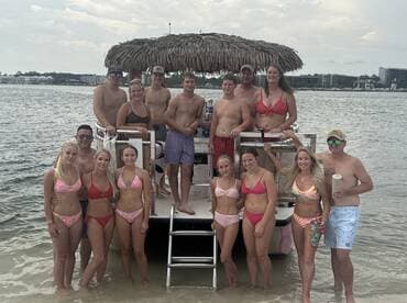 A lively group of friends poses on a pontoon boat, enjoying a fun day in the water — perfect for summer celebrations and beach outings.