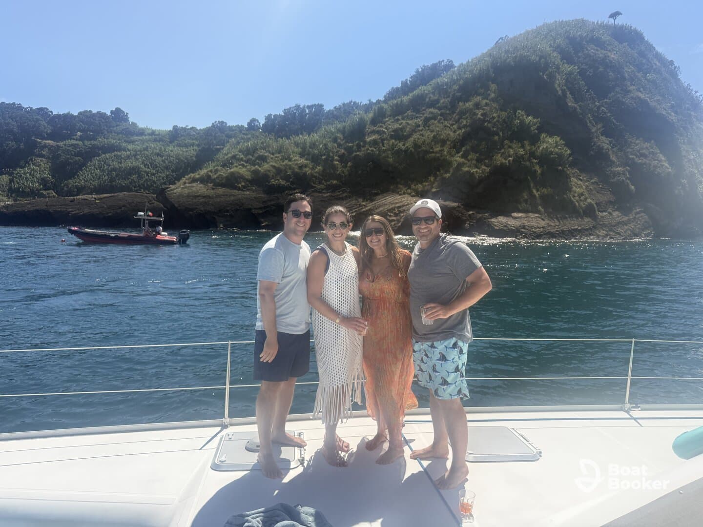 A cheerful group enjoys drinks on the deck of a boat, with stunning coastal scenery in the background — perfect for memorable outings and celebrations on the water.
