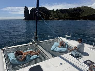 A couple relaxes on a catamaran, enjoying the serene ocean views and beautiful scenery — a perfect getaway for leisure and tranquility.