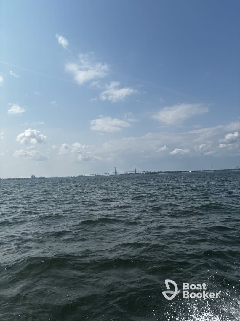 A scenic view of a bridge spanning across the water under a bright blue sky, showcasing the beauty of the coastline.