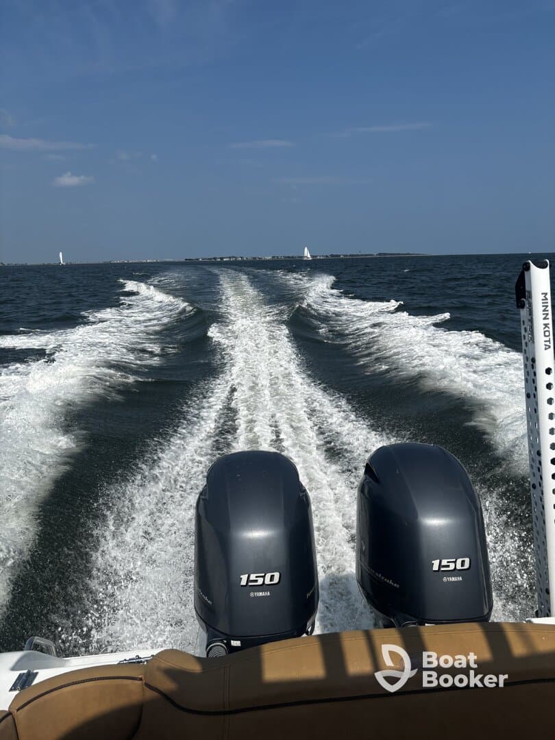 A dynamic view from the back of a speedboat, showcasing the powerful twin engines and the wake trailing behind as it navigates through open waters.