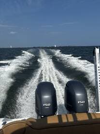A dynamic view from the back of a speedboat, showcasing the powerful twin engines and the wake trailing behind as it navigates through open waters.
