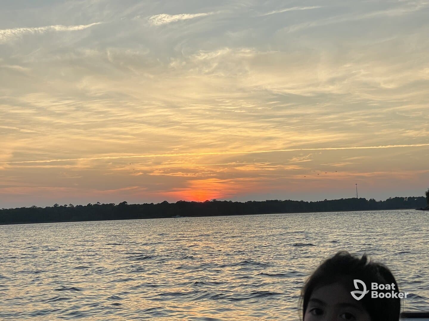 A beautiful sunset over the water with a child in the foreground, capturing a serene moment perfect for family outings on the boat.