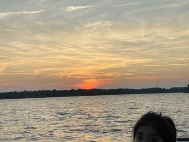 A beautiful sunset over the water with a child in the foreground, capturing a serene moment perfect for family outings on the boat.