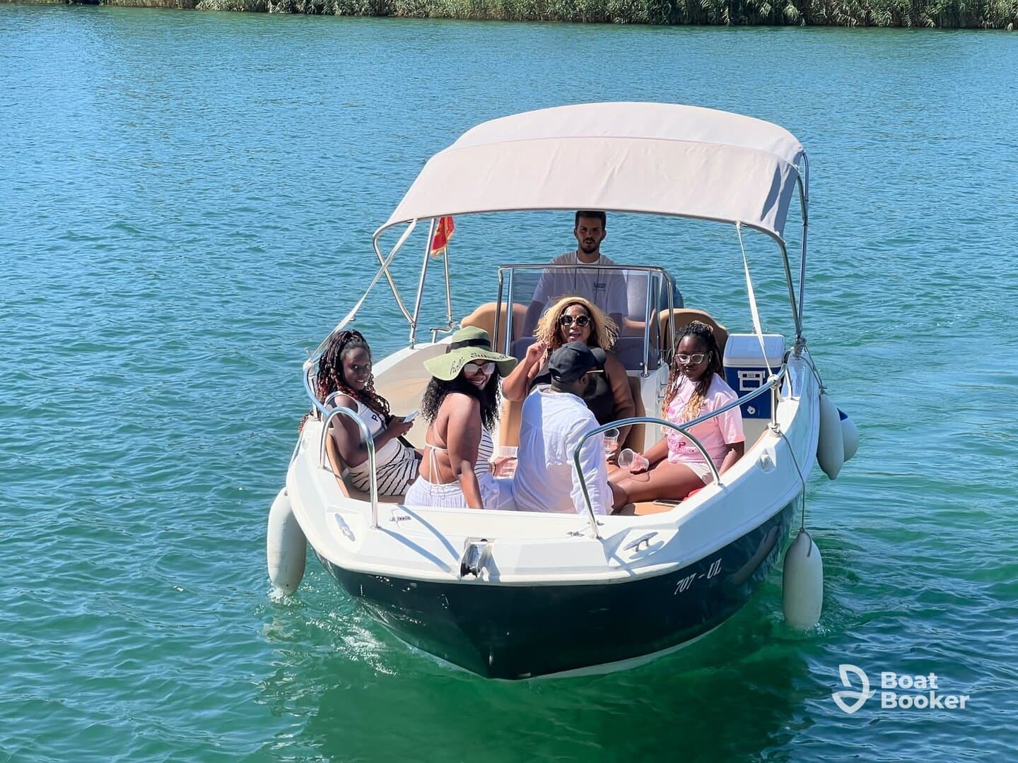 A lively group enjoys a day on the water aboard a boat, sharing drinks and laughter under the sun — perfect for a fun outing with friends.
