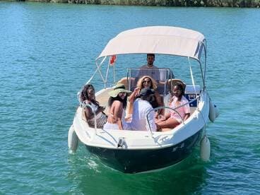 A lively group enjoys a day on the water aboard a boat, sharing drinks and laughter under the sun — perfect for a fun outing with friends.