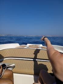 Guests enjoy a sunny day on the water, pointing towards a distant destination while relaxing on the boat — a perfect moment for adventure and exploration.