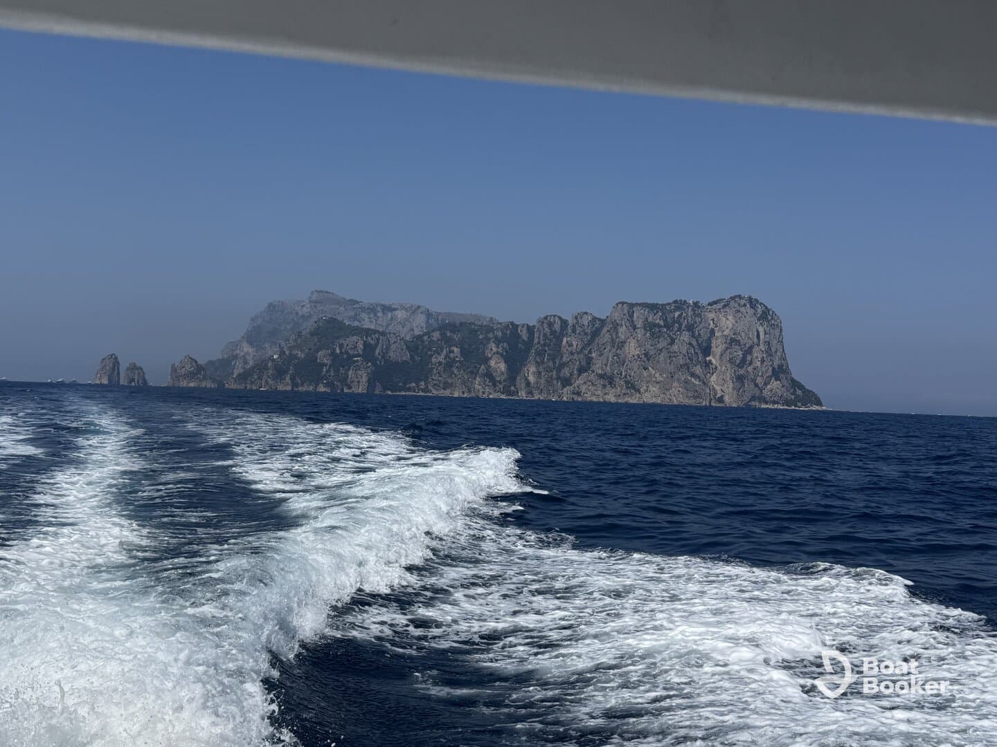 A stunning view of a rocky coastline and island from a boat, showcasing the beauty of the open sea and perfect for adventure seekers exploring coastal destinations.