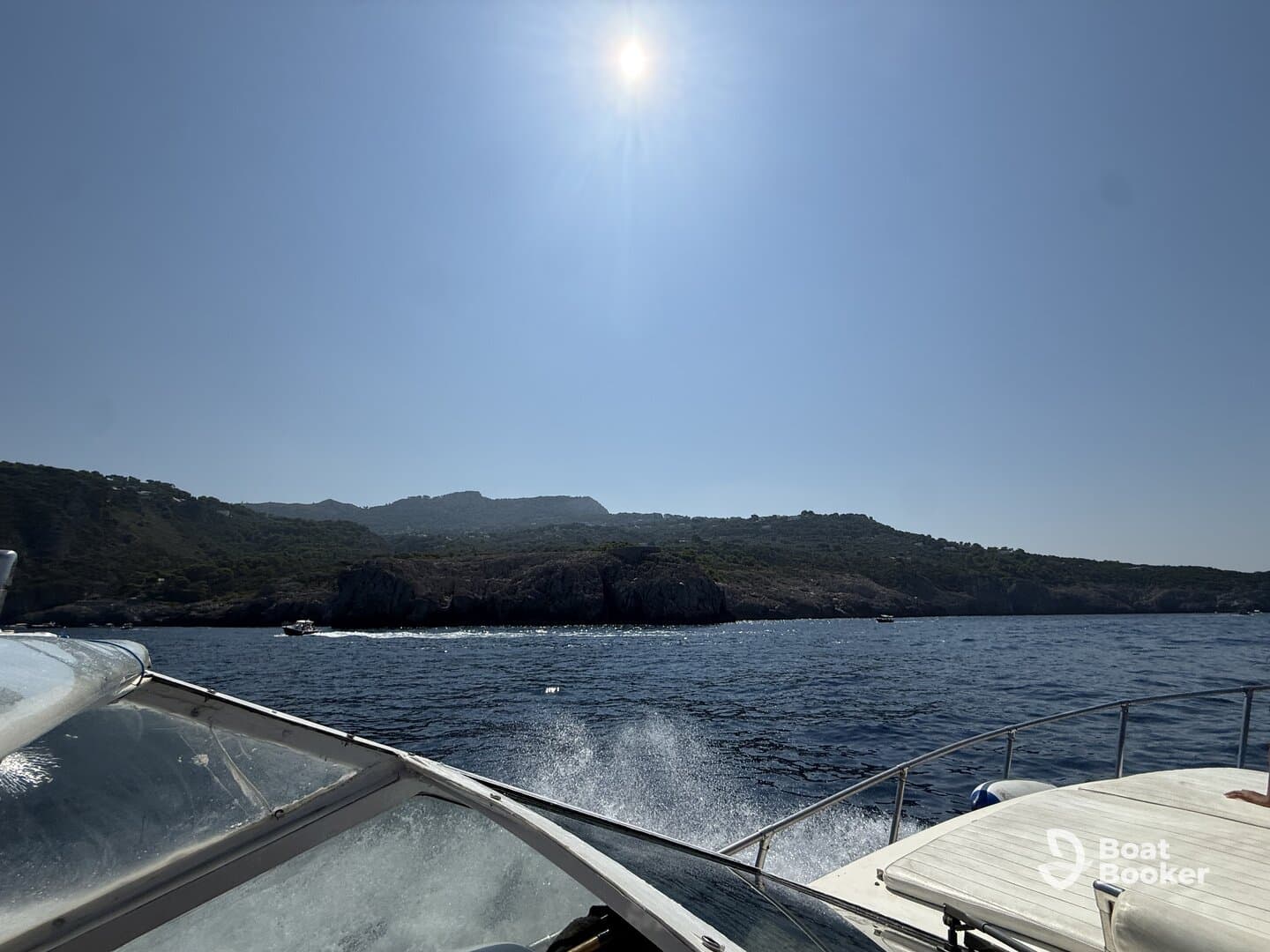 A scenic view from a boat cruising along a picturesque coastline under a clear blue sky, showcasing the beauty of the landscape and the thrill of being on the water.