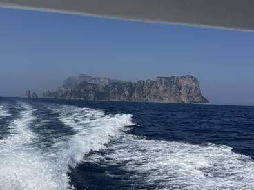 A stunning view of a rocky coastline and island from a boat, showcasing the beauty of the open sea and perfect for adventure seekers exploring coastal destinations.