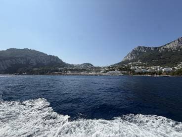 A stunning view of the coastline and hills of Capri, showcasing the beautiful landscape and crystal-clear waters — perfect for island-hopping adventures.