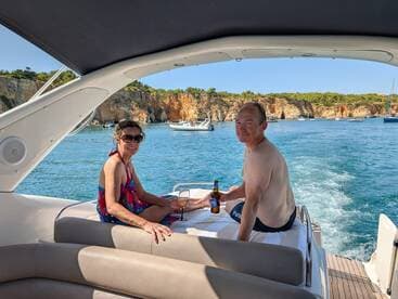 A couple enjoys drinks on a boat while taking in the stunning coastal scenery — perfect for a relaxing day on the water.