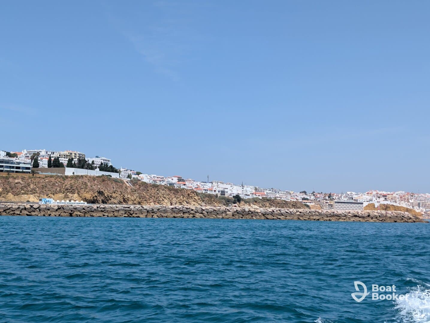 A picturesque view of a coastal town from the water, showcasing the beautiful shoreline and vibrant buildings — perfect for capturing the essence of a seaside getaway.