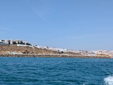 A picturesque view of a coastal town from the water, showcasing the beautiful shoreline and vibrant buildings — perfect for capturing the essence of a seaside getaway.