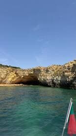 A stunning view of a coastal cave with a sandy beach, where visitors can be seen enjoying the picturesque scenery — a perfect spot for exploration and relaxation.