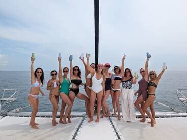 A lively group of women celebrates on the deck of a catamaran, raising their drinks in a fun-filled party atmosphere — perfect for bachelorette trips or summer getaways.