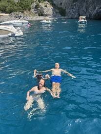 A joyful family enjoys swimming in crystal-clear waters, creating unforgettable memories on their boating adventure.