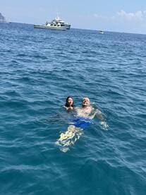 A couple enjoys a refreshing swim in the ocean with a boat in the background, capturing the essence of a perfect day on the water.