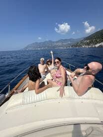 A joyful group enjoys a sunny day on the water, celebrating together aboard a boat with stunning coastal views in the background.