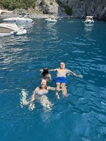 A joyful family enjoys swimming in crystal-clear waters, creating unforgettable memories on their boating adventure.