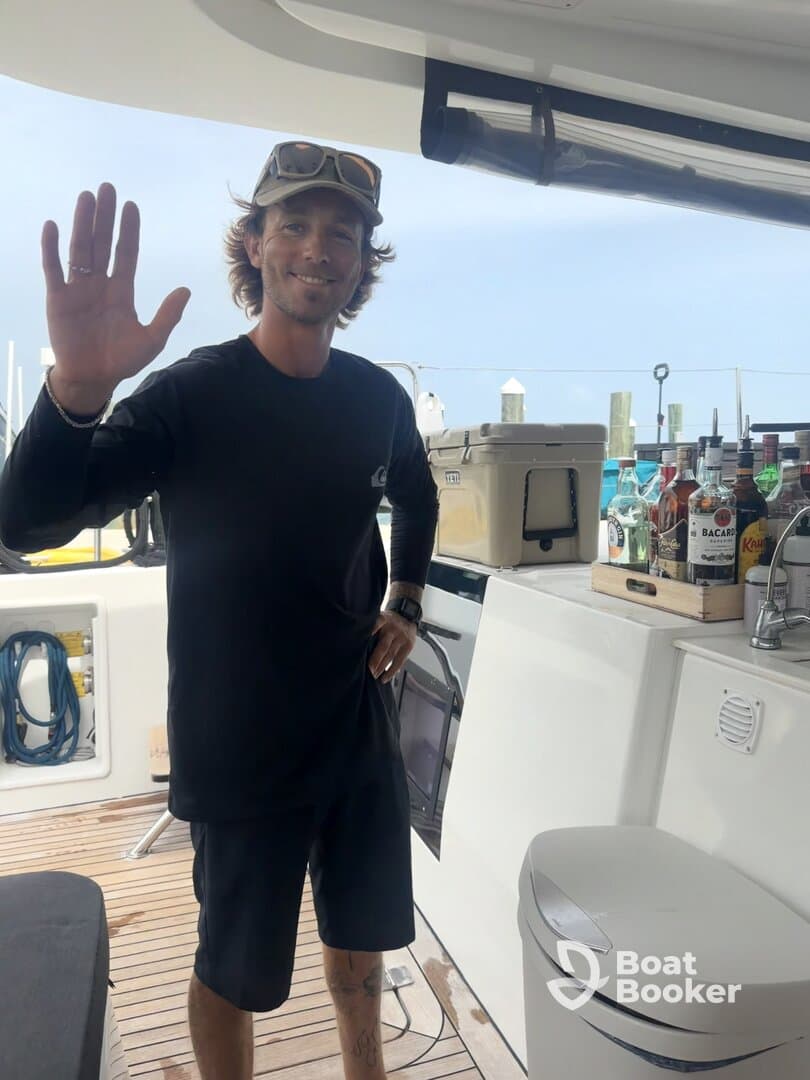 A friendly crew member greets guests aboard the boat, showcasing the interior space with a well-stocked bar area — perfect for entertaining on the water.